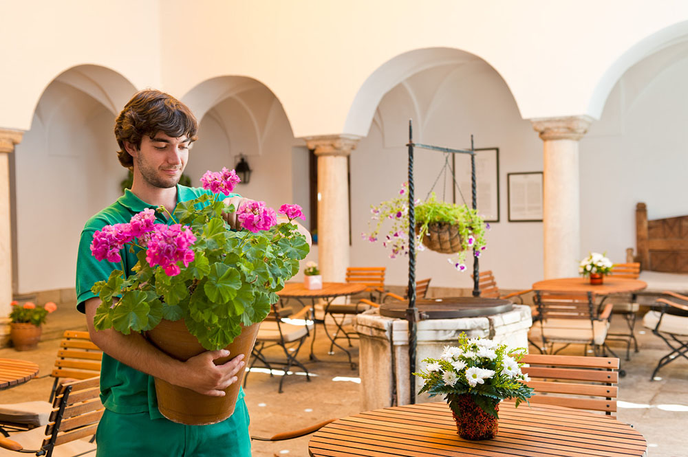A member of staff carefully tending the geraniums in the patio of the Parador de Merida © Michelle Chaplow